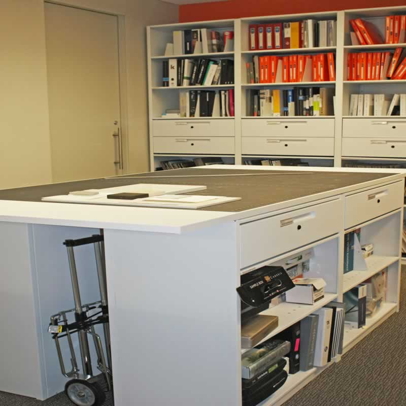 A compact shelving system involves a series of cabinets or racks that are attached to wheeled carriages.