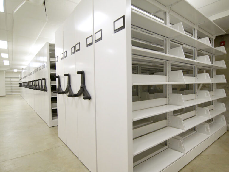 Mobile storage shelving systems consolidate rows of shelving while sharing a movable access aisle.